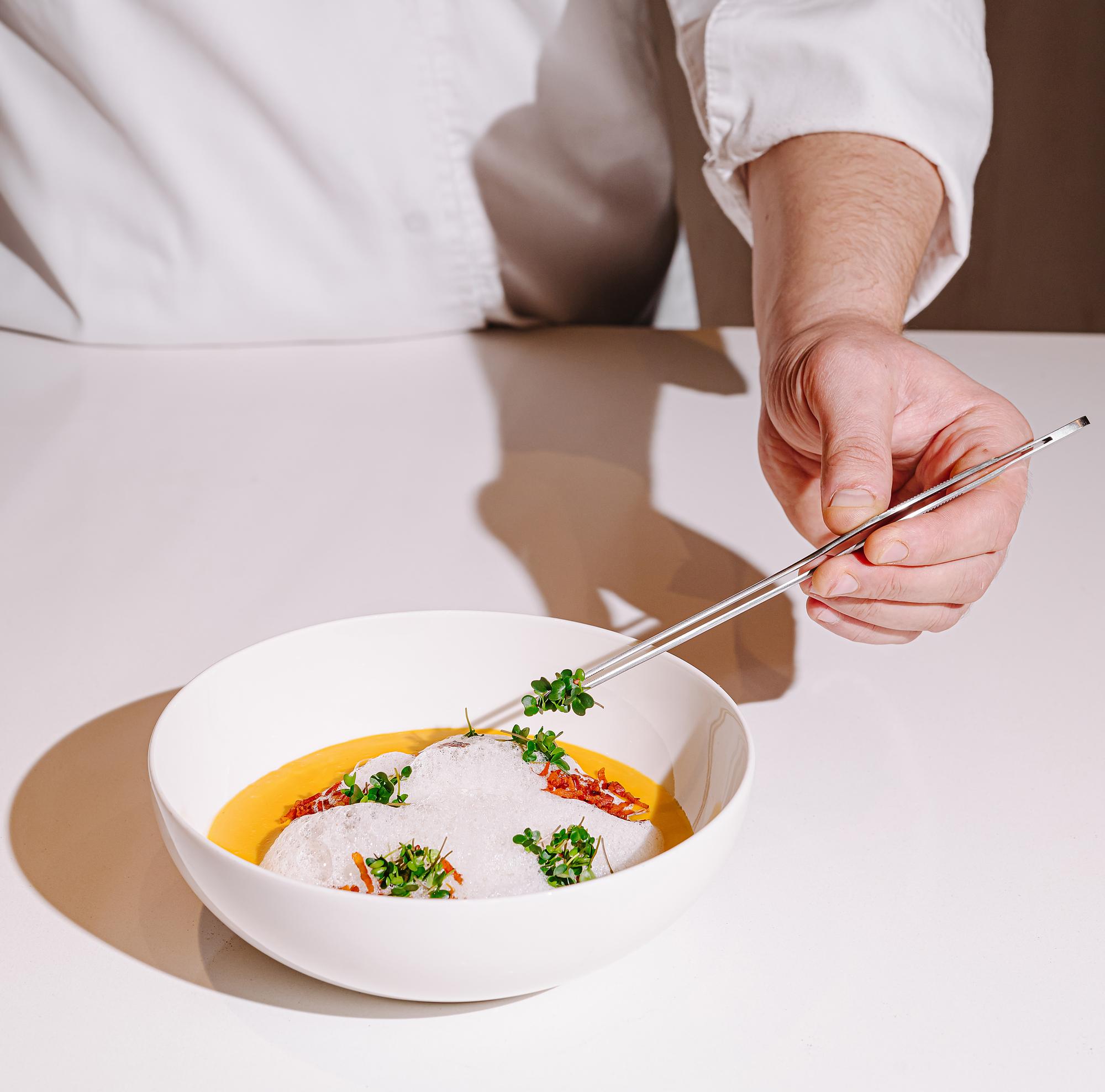 Chef arranging plated dish in warm kitchen